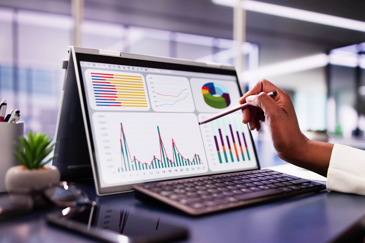 African American woman analyzing financial data on laptop screen in hybrid office setting